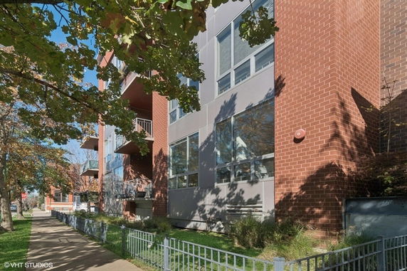 Front view of a modern multi-story brick building with large windows.
