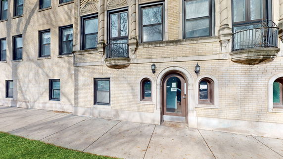 Front view of a multi-story brick building with ornate window details and a main entrance door.