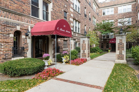Front view of a multi-story brick apartment building with red awnings.