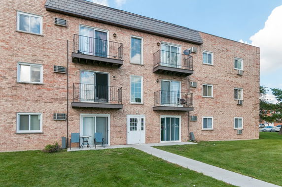 Front view of a multi-story brick apartment building with balconies.