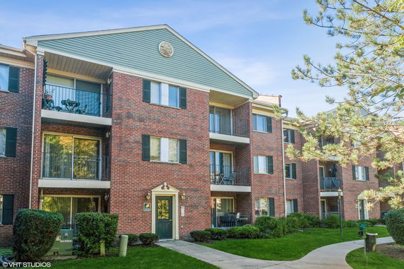 Front view of a multi-story brick apartment building with balconies.