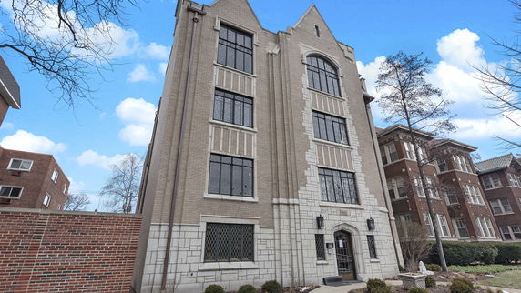 Front view of a multi-story brick building with large windows and decorative stone elements.