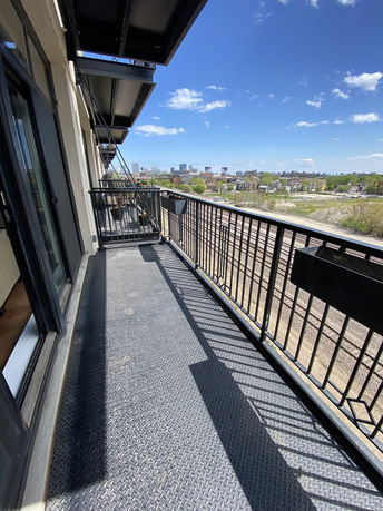 View from a balcony overlooking railway tracks and distant buildings under a clear sky.
