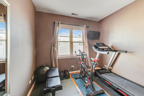Indoor fitness area with exercise bike, treadmill, and bench.