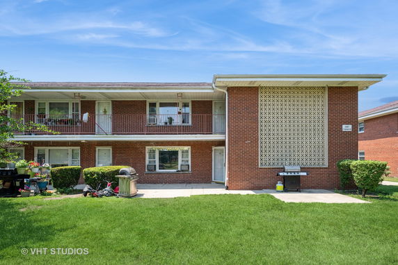 Front view of a two-story brick apartment building with balcony.