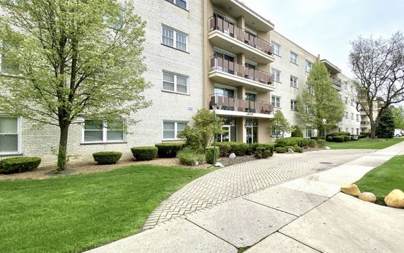 Front view of a multi-story apartment building with balconies and landscaping.