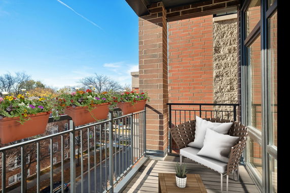 Balcony view with flowers on railing and outdoor seating.