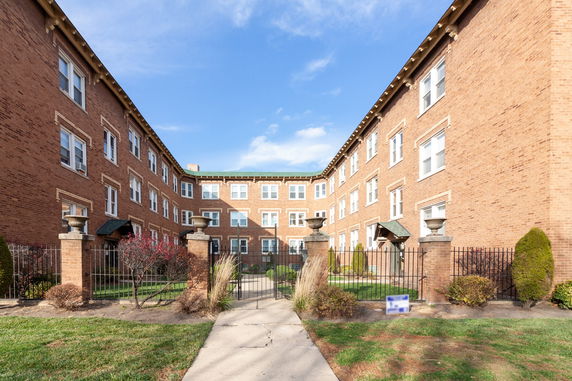 Front view of a multi-story brick building with an entrance gate.