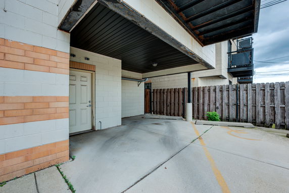 Outdoor covered parking area with marked spaces next to a building.