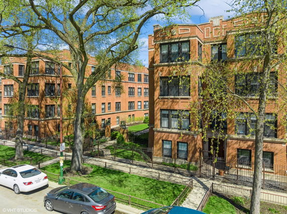 Front view of a multi-story brick apartment building with large windows.