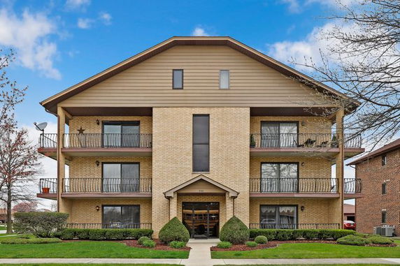 Front view of a three-story building with balconies and a gabled roof.