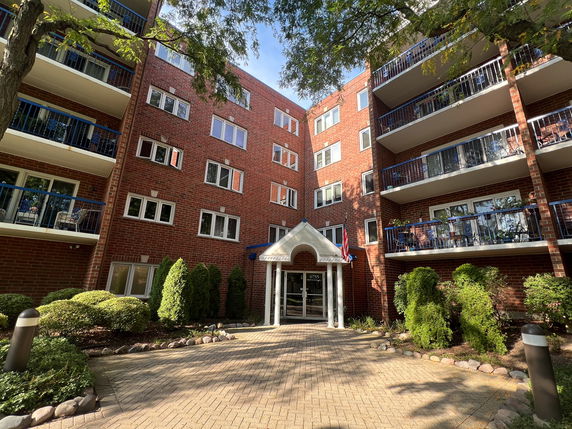 Front view of a multi-story brick apartment building with balconies.