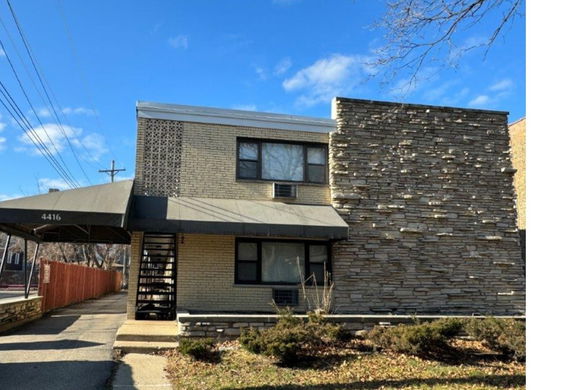 Front view of a two-story brick house with stone wall siding.