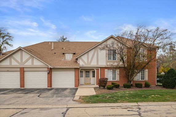 Front view of a two-story house with a three-car garage and brick exterior.