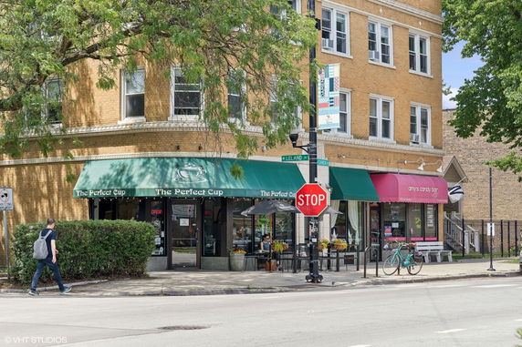 Front view of a brick building with storefronts and green awnings.