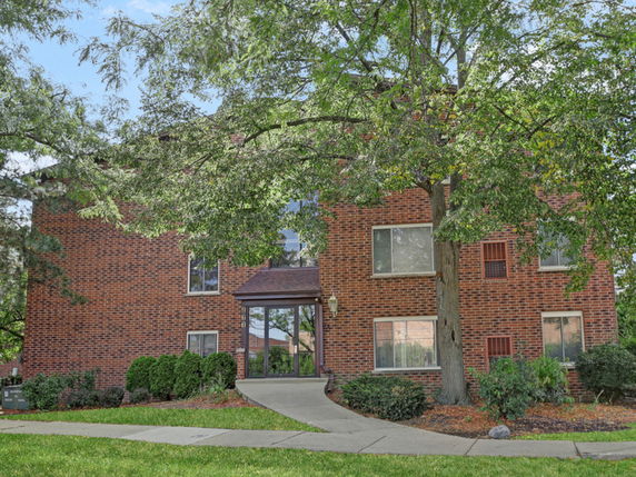 Front view of a multi-story brick building with large windows.