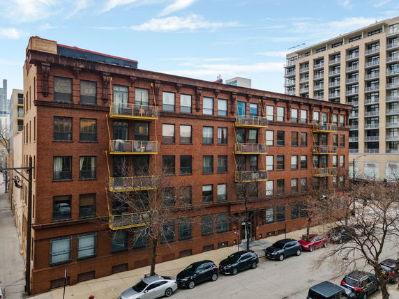 Front view of a multi-story brick apartment building with balconies.