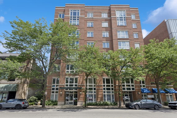 Front view of a multi-story brick building with large windows.