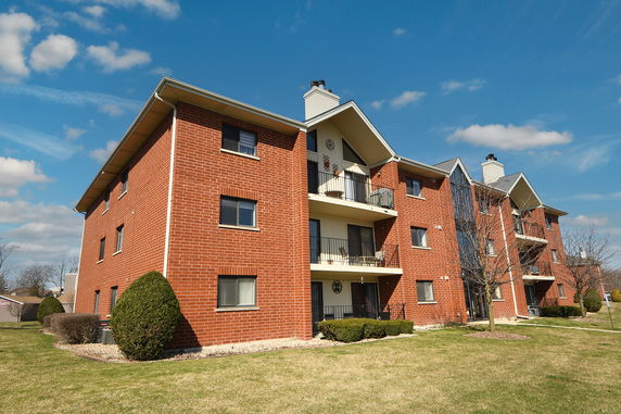 Front view of a multi-story brick apartment building with balconies.