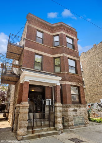Front view of a multi-story brick building with a gated entrance.