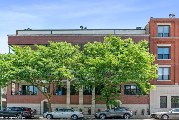 Front view of a multi-story brick building with trees partially obscuring the facade.
