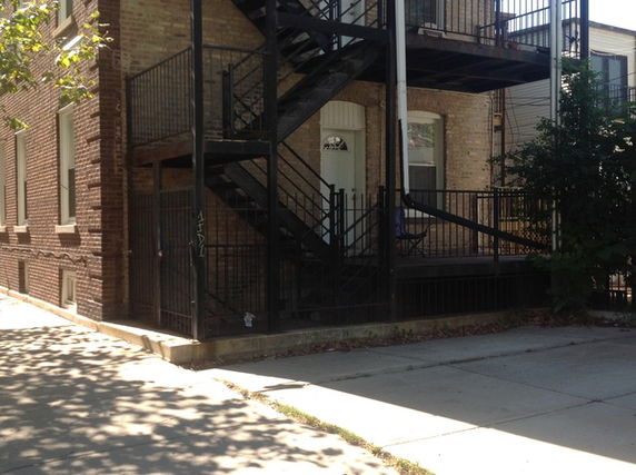 Front view of a brick building with metal stairs and railings.