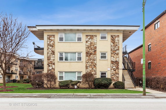 Front view of a three-story apartment building with a mix of brick and stone facade.