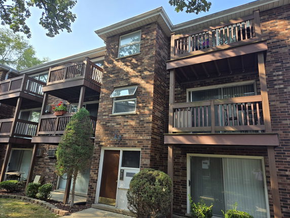 Front view of a multi-story brick building with balconies.