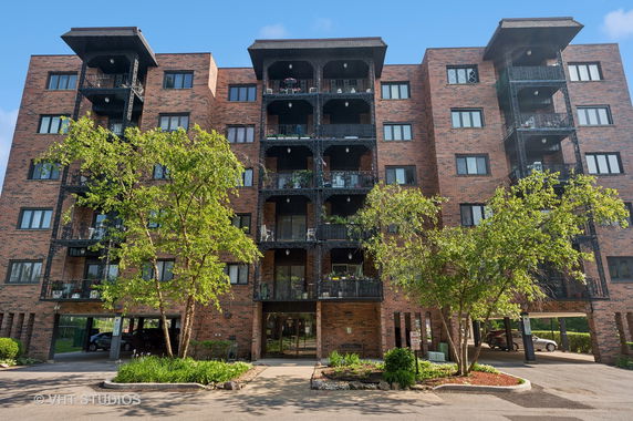 Front view of a multi-story brick apartment building with balconies.