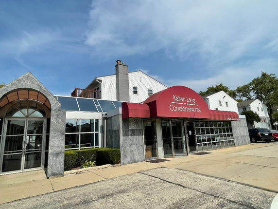 Front view of a condominium building with a red awning entrance.