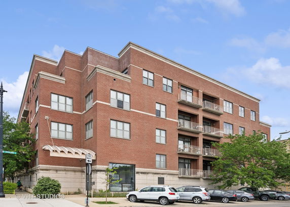 Front view of a multi-story brick apartment building with balconies.