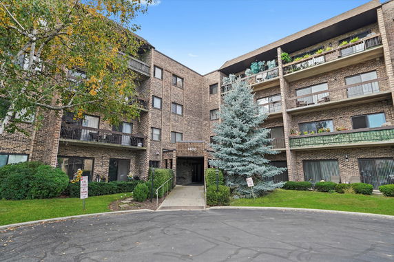 Front view of a multi-story brick residential building with balconies.