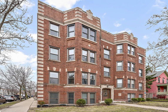 Front view of a multi-story brick apartment building with multiple windows.