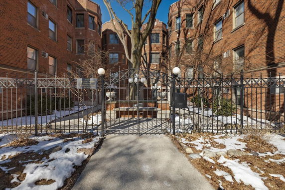 Front view of a brick multi-story building with a gated entrance.