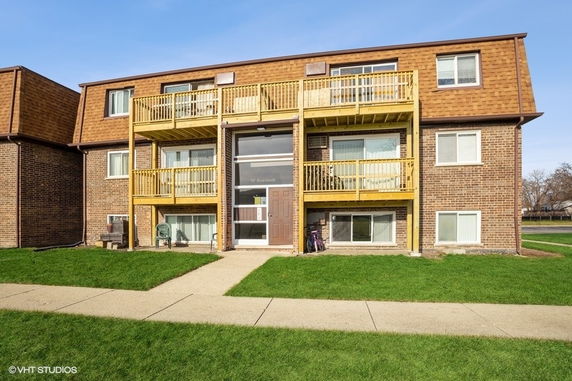 Front view of a two-story brick apartment building with balconies.