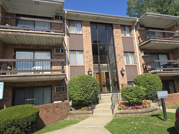 Front view of a multi-story brick apartment building with balconies.