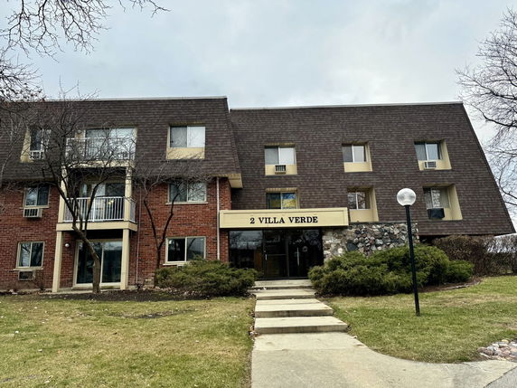 Front view of a three-story residential building labeled '2 Villa Verde' with a brick and shingle exterior.