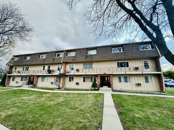 Front view of a three-story residential building with multiple windows and balconies.