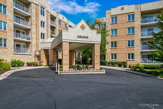 Front view of a multi-story residential building with balconies and an entrance canopy.