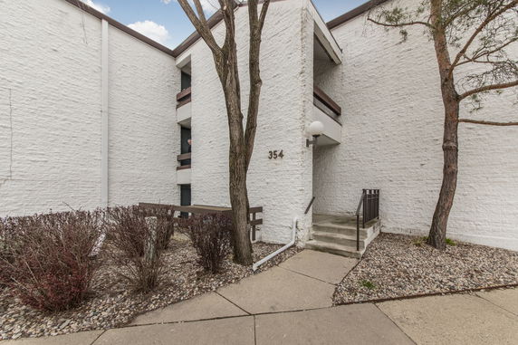 Front view of a multi-story building with white brick walls and a staircase.