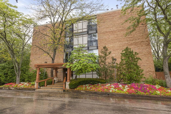 Front view of a multi-story brick building with a wooden entrance canopy.