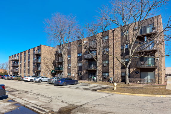 Front view of a multi-story brick apartment building with balconies.