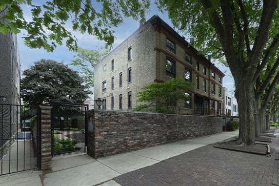 Front view of a multi-story brick building with a gated entrance.