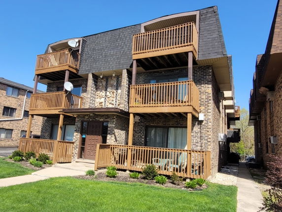Front view of a multi-story brick building with wooden balconies and a central entrance.