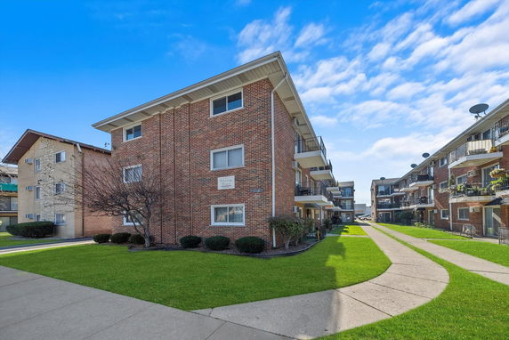 Front view of a three-story brick apartment building with balconies.