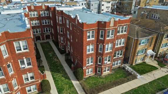 Front view of a multi-story brick apartment building with white-framed windows.