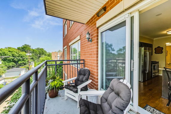 Balcony view from an apartment with chairs overlooking green tree-filled surroundings.