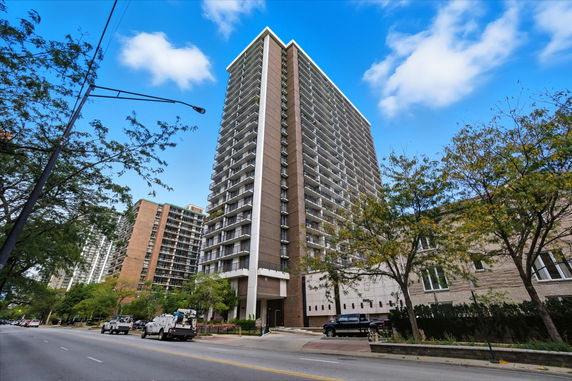 Front view of a tall residential building with multiple balconies.