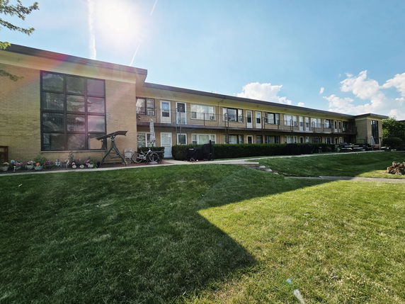 Front view of a multi-story building with balconies and large windows.