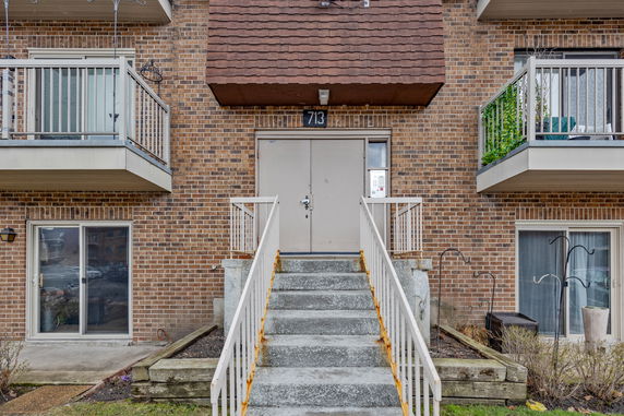 Front view of a building entrance with stairs and balconies.